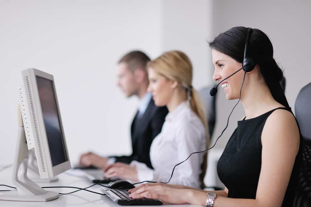 Three call-center agents wearing headsets, working at their computers.
