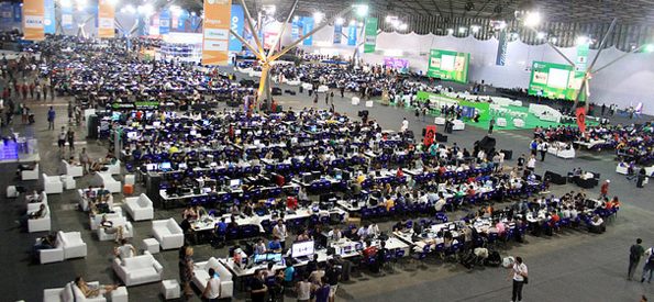 Wide view of the Campus Party tech event venue, with rows of desks and a large crowd of attendees.
