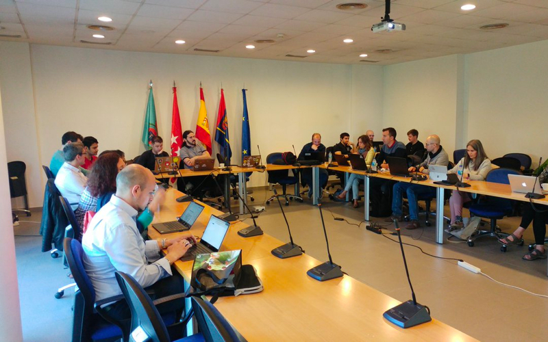 ElasTest project consortium meeting in a conference room, partners working on laptops.