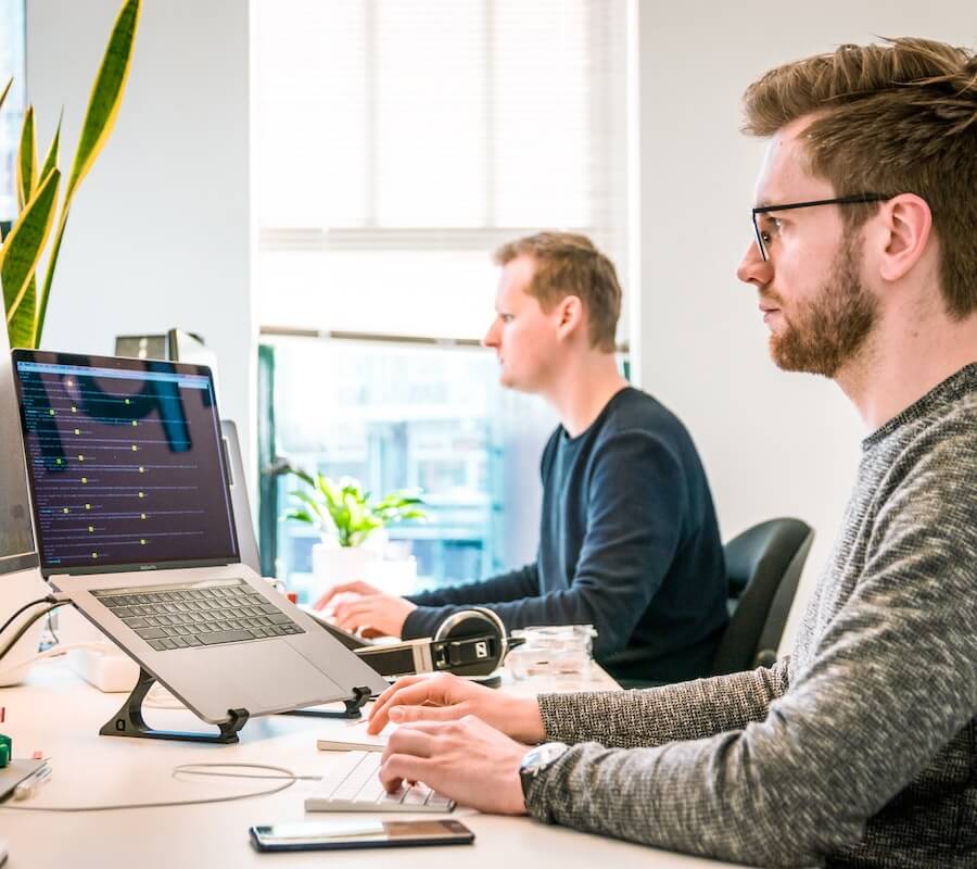 Two developers working on laptops in an office.