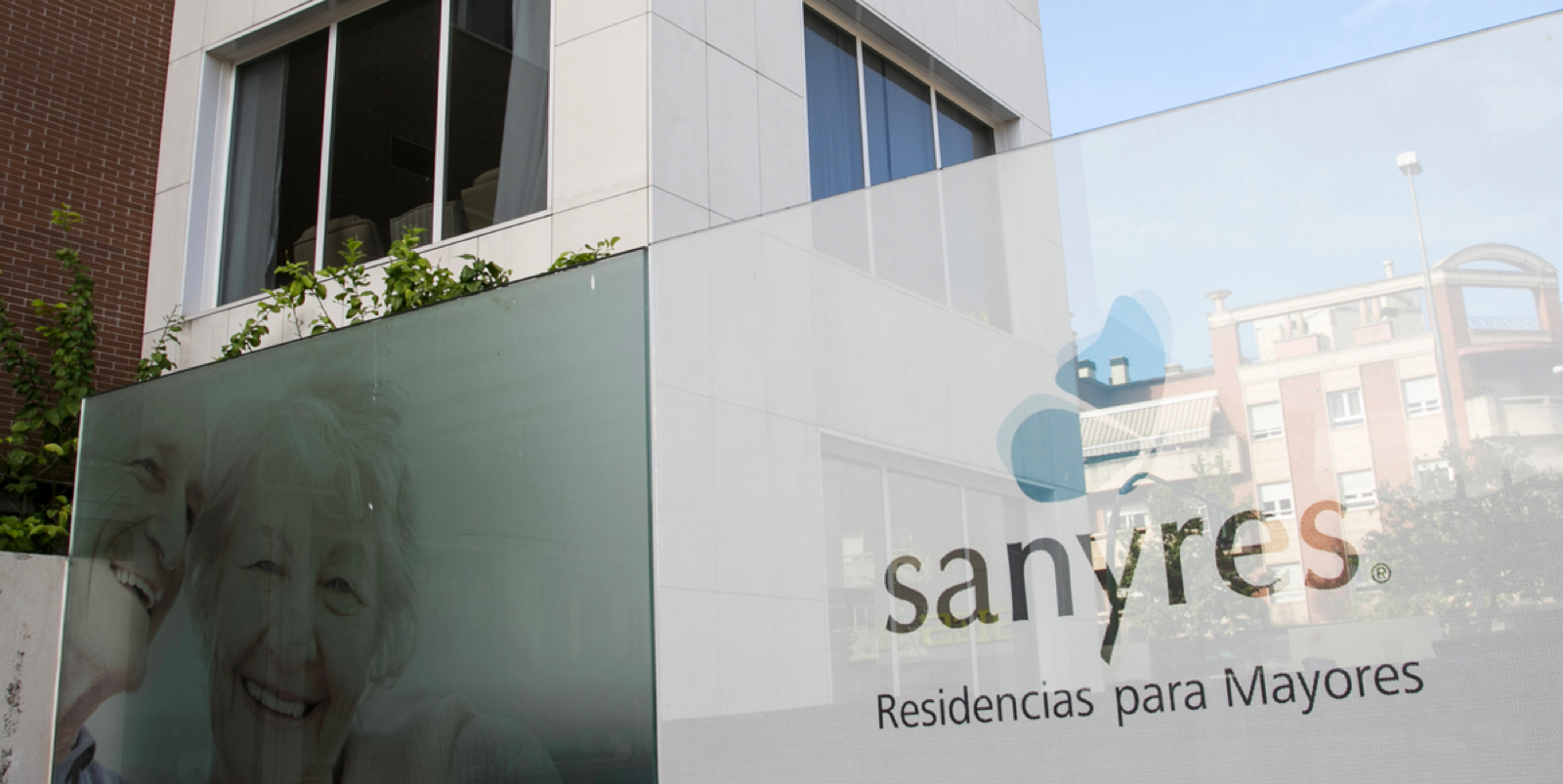 Exterior of a Sanyres nursing home building with a sign reading 'Residencias para Mayores' and a photo of smiling residents.