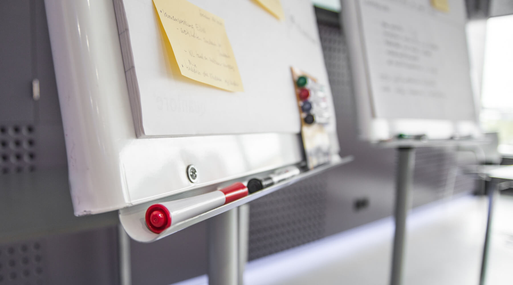 Whiteboards with sticky notes and markers in a meeting room.